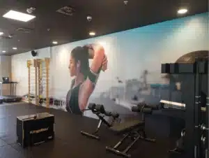 Zidna tapeta s motivom atletičarke koja se isteže u modernoj teretani