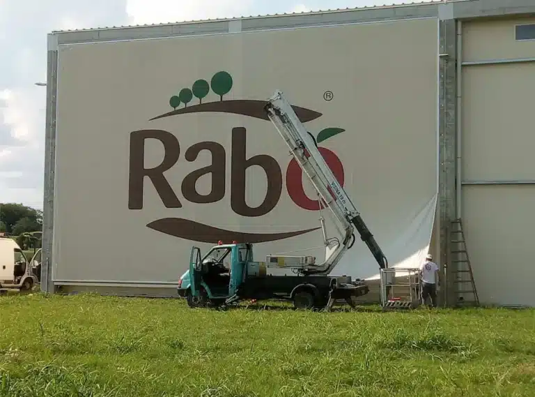 Montaža XXL reklamne cerade s tiskom na pročelje industrijskog objekta dizalicom – veliki format bannera