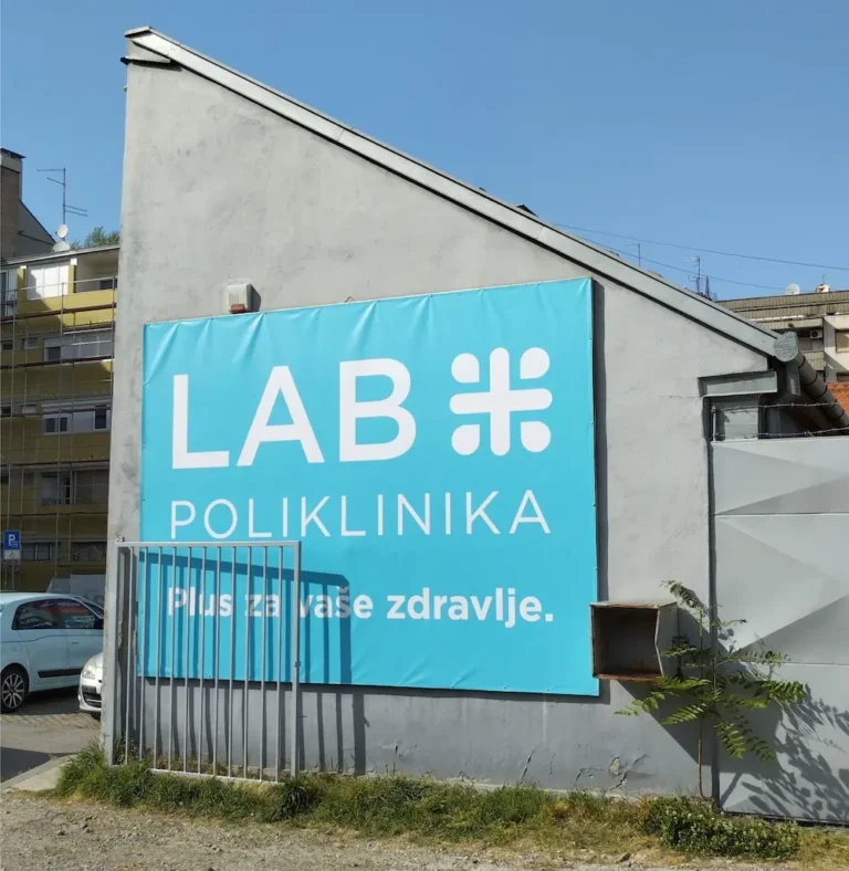 Reklamna cerada na fasadi s tiskom logotipa i poruke – veliki vanjski banner za zdravstvene i poslovne ustanove