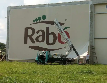 Montaža XXL reklamne cerade s tiskom na pročelje industrijskog objekta dizalicom – veliki format bannera